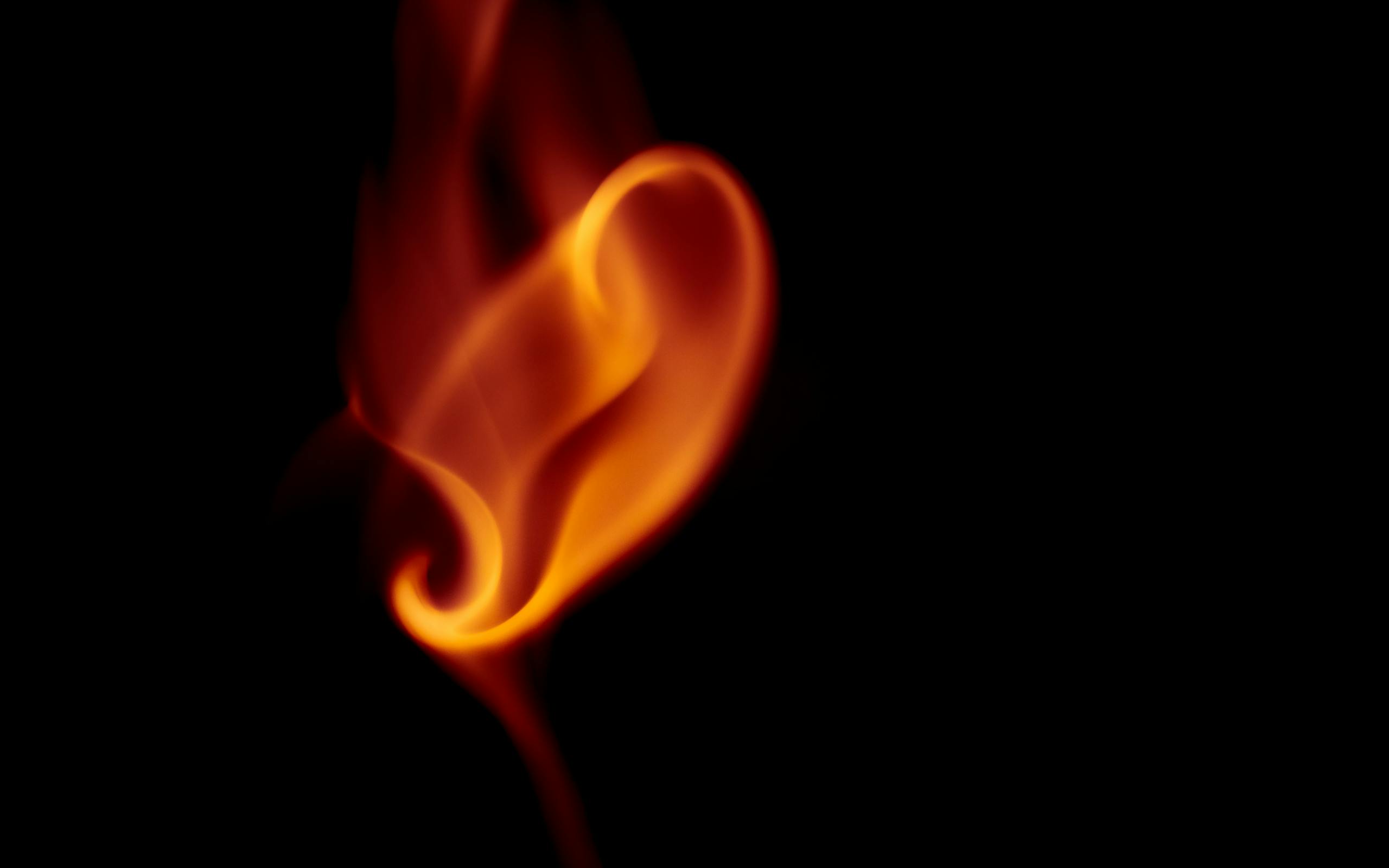 A swirling orange flame against a black background, capturing heat and movement.