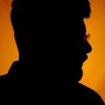 Dramatic silhouette of a man's profile with an amber background, conveying mystery and depth.